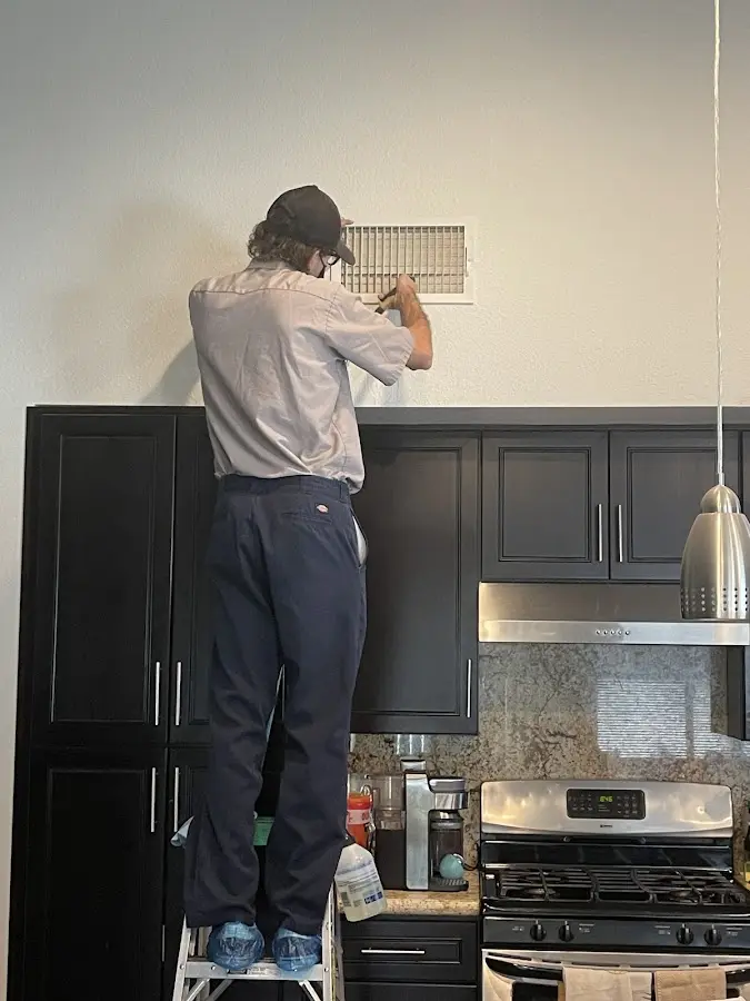 Technician inspecting an air vent during HVAC service in Newmarket